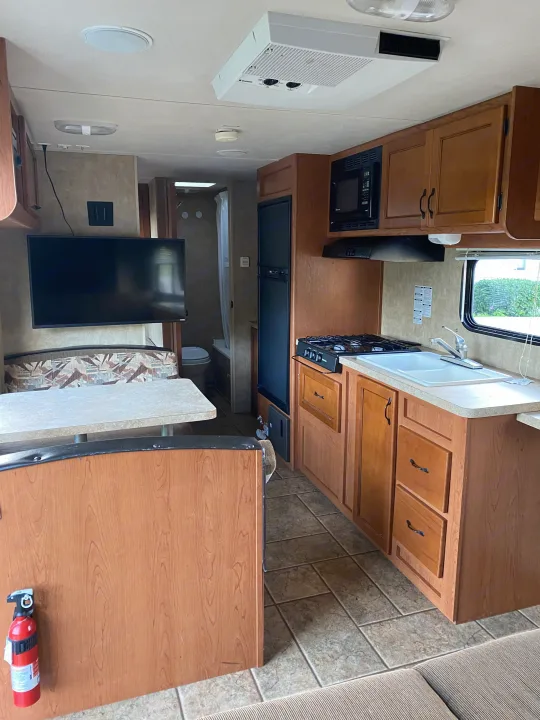 RV rental interior showing kitchen, dinette, & bathroom. Features TV, AC, & modern finishes.. Forest River Cherokee Grey Wolf 2012