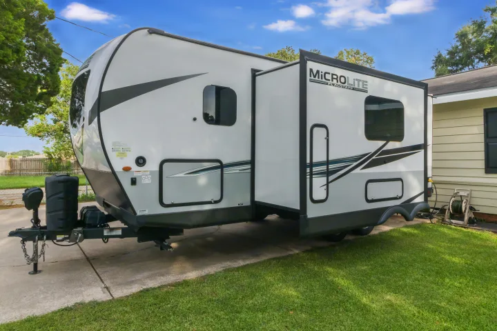 This white and gray Microlite Flagstaff RV, with its slide-out extended, is ready for your next rv rental adventure, parked on a sunny driveway.. Forest River Flagstaff Micro Lite 2022