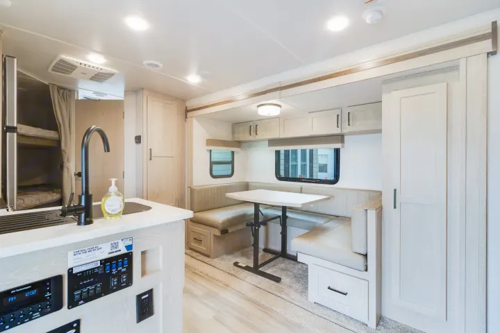 Bright, modern RV rental interior with kitchen, U-shaped dinette, and bunk beds, highlighting ample space for living.. Forest River Flagstaff Micro Lite 2022