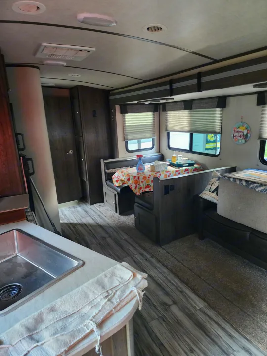 Inside an RV rental: a spacious dinette with a fruit-patterned tablecloth, kitchen sink, and cozy living area.. Cruiser RV MPG Ultra Lite 2020