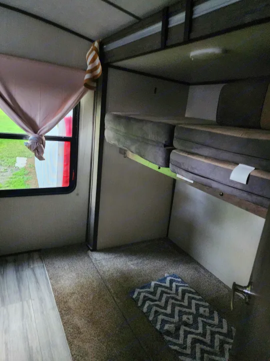 An RV rental interior featuring compact bunk beds and a window with a tied curtain. Perfect for camper travel.. Cruiser RV MPG Ultra Lite 2020