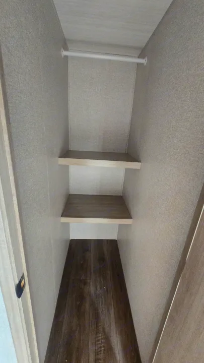Empty RV rental closet with two shelves, a hanging rod, and wood-look floor for storage.. East to West Alta 2022