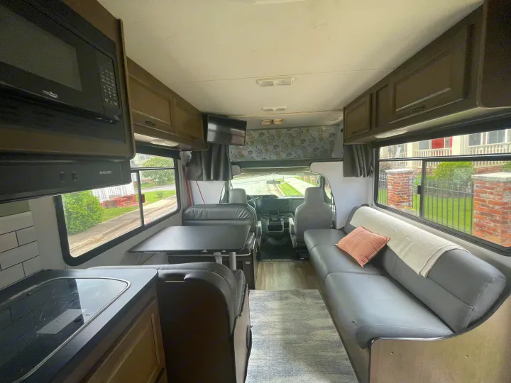 RV rental interior: kitchen, dinette, lounge sofa, and forward cockpit. Includes overhead storage & TV.. Thor Majestic 2019
