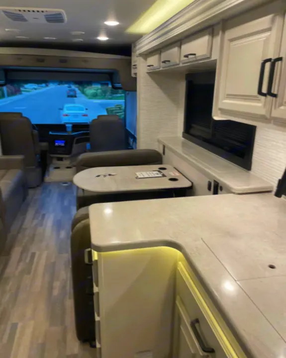 Modern rv rental interior showing cockpit, dinette, and bright kitchen with light counters and flooring.. Entegra Coach Other 2024
