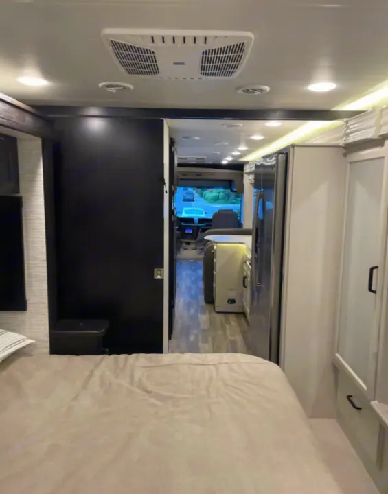 View from the RV rental bedroom, looking down the hallway past the kitchen area towards the front cockpit. Features a modern interior.. Entegra Coach Other 2024