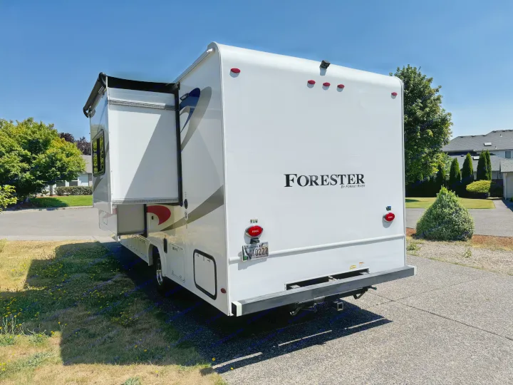 Rear view of a white Forester RV rental on a sunny day, parked on asphalt with an extended slide-out. Perfect for your next adventure.. Forester Forester Motorhome 2019