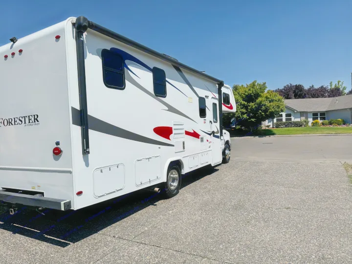 A clean, white Forester RV rental with bold red and blue graphics, parked on asphalt under a clear blue sky.. Forester Forester Motorhome 2019