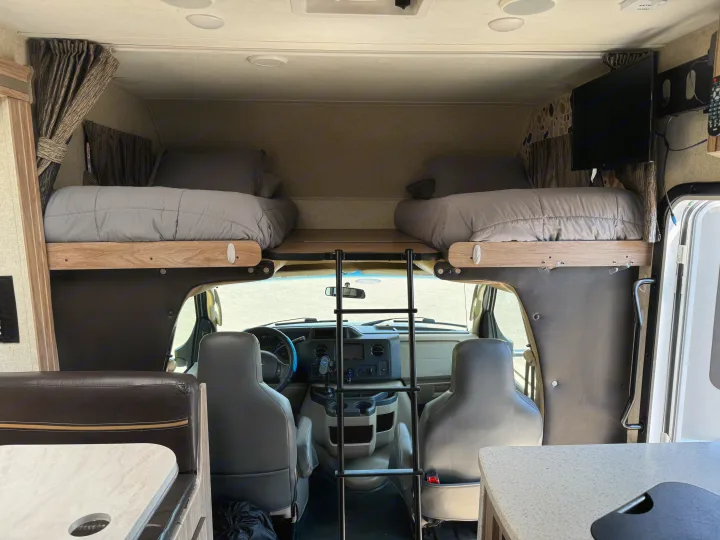 Inside an RV rental: forward view showing the cockpit, a ladder to the cab-over bunk beds, and a cozy dinette.. Forester Forester Motorhome 2019