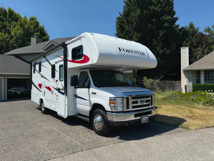 Sunny day view of a bright white Forest River Forester Class C **rv rental** parked on a paved driveway, ready for adventure.. Forester Forester Motorhome 2019