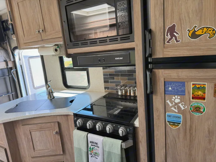 RV rental kitchen interior: wood cabinets, sink, stove, microwave, and fridge adorned with fun travel magnets.. Forester Forester Motorhome 2019