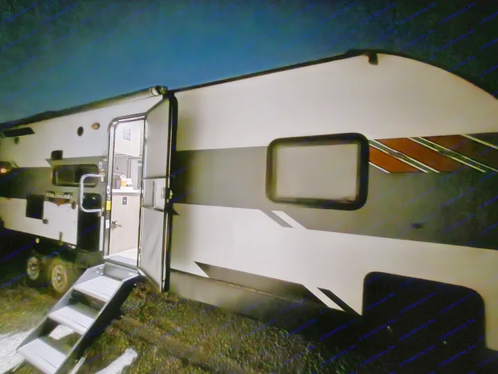 RV rental at night with its door open, showing a lit interior and steps, ready for adventure.. Forest River Wildwood 2021
