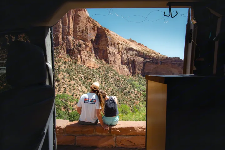 Scenic stop: A couple overlooks red rock mountains from their RV rental. Fairy lights string above.. Ford transit 2017