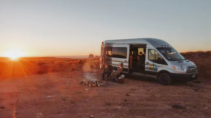 RV rental: Family enjoys a campfire next to their WanderVans campervan at desert sunset.. Ford Transit 350 2021