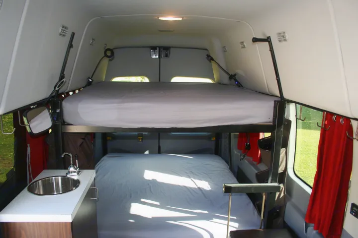 Cozy RV rental interior featuring bunk beds, a small kitchen sink, and clever storage solutions.. Ford Transit 350 2021