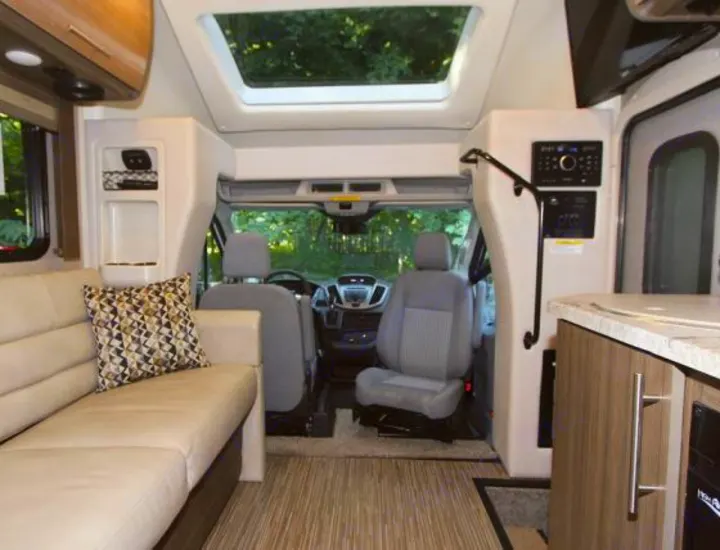 Interior of a clean rv rental, showing the driver's area, comfortable sofa, and kitchenette. Ready for your next adventure.. Thor Gemini 2017