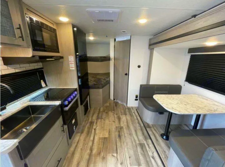 Explore this spacious RV rental interior featuring a modern kitchen, cozy dinette, and convenient bunk beds.. Dutchmen Coleman 1905BH 2024