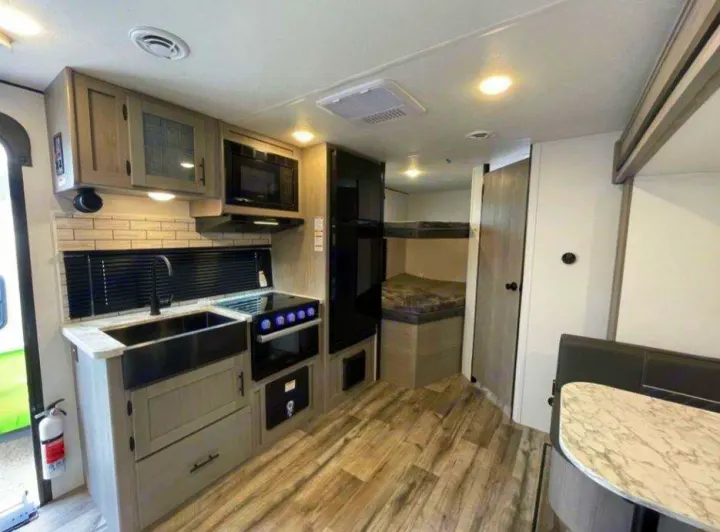 RV rental interior: fully-equipped kitchen, large refrigerator, bunk beds, and dinette. Ready for your next adventure.. Dutchmen Coleman 1905BH 2024