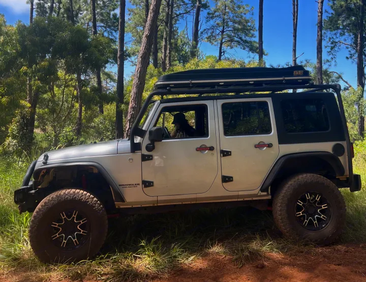 Adventure-ready Jeep Wrangler with rooftop tent on a forest trail. A perfect alternative to an RV rental for off-road camping.. Jeep Wrangler 2008