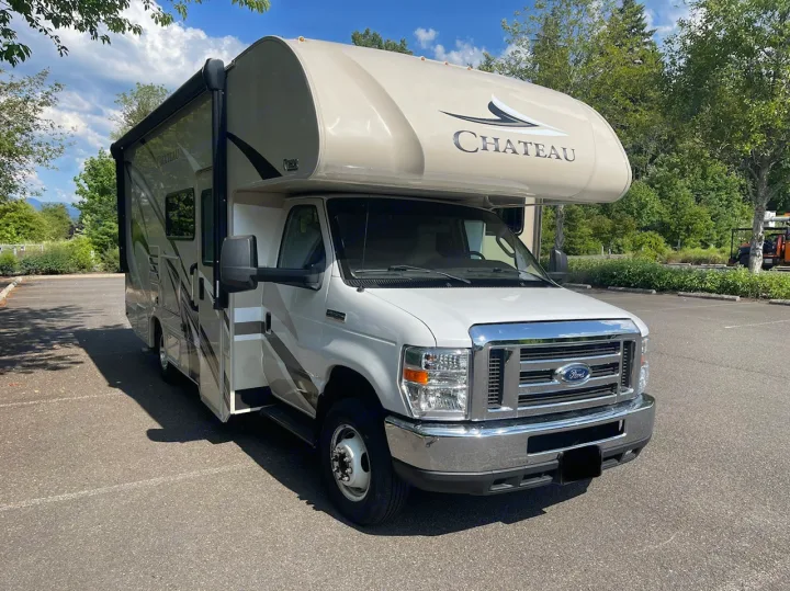 This white and tan Chateau Class C RV rental is parked in a sunny lot, ready for your next travel adventure.. Thor Chateau 2019