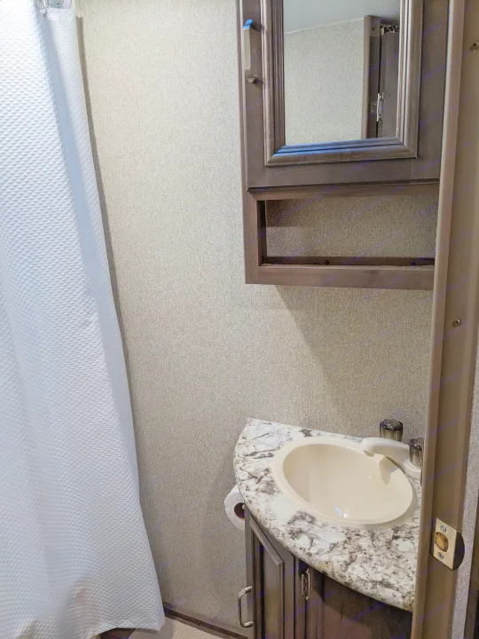 View of a compact RV rental bathroom with shower, vanity, sink, and mirrored medicine cabinet.. Keystone RV Passport Ultra Lite 2018
