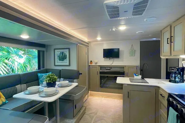 Modern RV rental interior: U-shaped dining booth, living area with TV/fireplace, and a full kitchen.. Forest River Salem Cruise Lite 2023