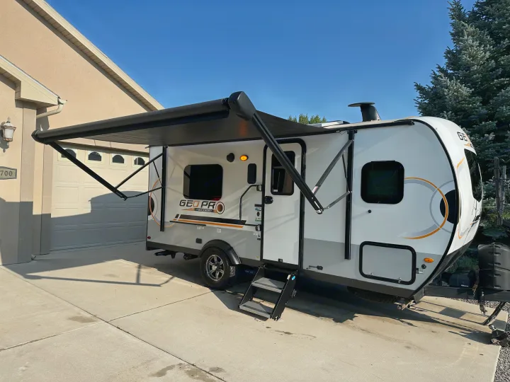 A white & grey Geo Pro travel trailer with extended awning, perfect for an rv rental outdoor adventure, parked in a sunny driveway.. Forest River GeoPro 2022