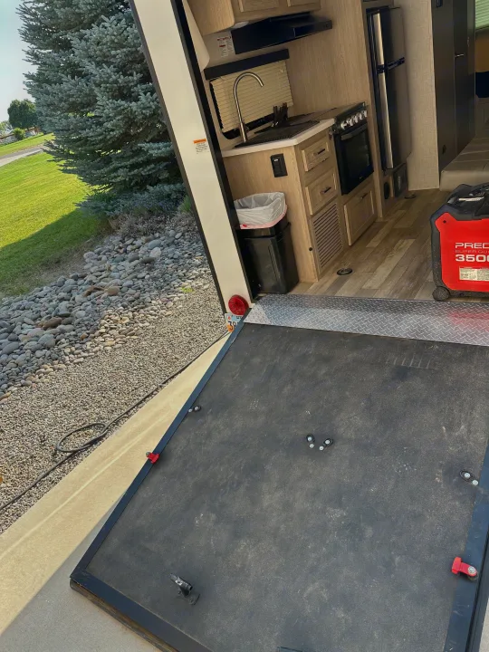 Inside an RV rental featuring a compact kitchen, portable generator, and the rear ramp extended to a scenic outdoor area.. Forest River GeoPro 2022