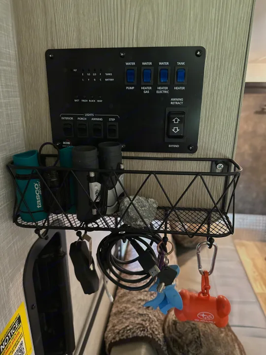 An RV rental's control panel (water, lights, awning) and a mounted basket with binoculars, keys, and a Subaru keychain.. Forest River GeoPro 2022