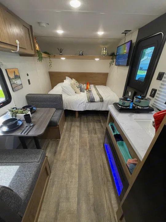 Interior of a modern and comfortable RV rental, featuring a full bed, dinette, and compact kitchen area.. Forest River Wolf Den 16EV 2024