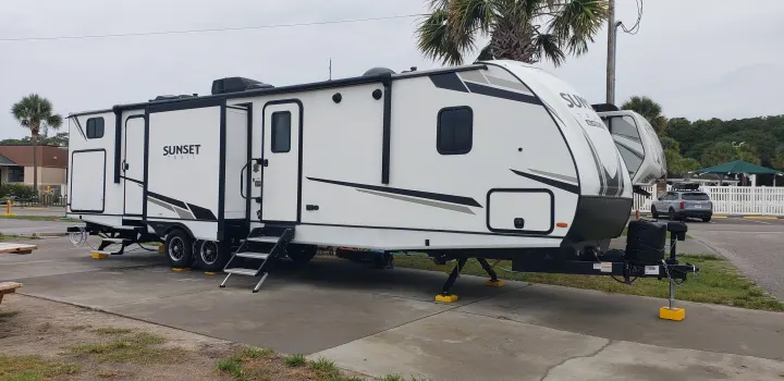 This white Sunset Trail RV rental is fully setup at a paved campsite, stable on yellow blocks.. Keystone Sunset Trail 2022