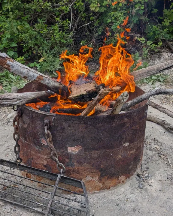 Bright campfire in a rusty barrel fire pit, surrounded by nature. Enjoy cozy evenings on your RV rental trip.. Forester Forester Motorhome 2019