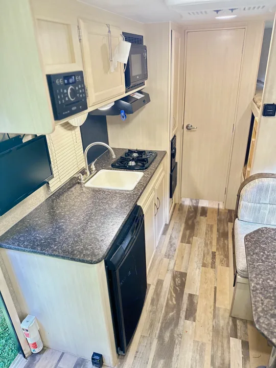 RV rental kitchen and living area, showcasing a sink, stove, microwave, fridge, TV, stereo, and dinette. Perfect for road trips.. Minnie Micro Minnie 2018