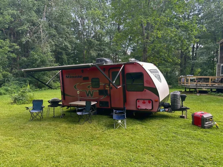Winnebago Micro Minnie RV rental set up for camping with an extended awning, outdoor chairs, grill, and generator.. Minnie Micro Minnie 2018