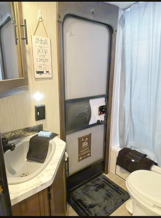 Compact RV rental bathroom featuring a sink, toilet, shower, and a humorous "Thou shalt NOT poop in the camper" sign.. Forest River Cherokee Grey Wolf 2021