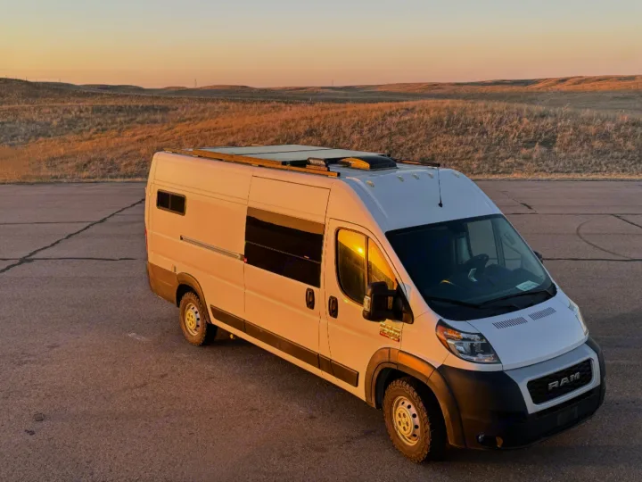White Ram ProMaster camper van, an RV rental, bathed in golden sunset light for your next adventure.. Custom Ram Promaster 2021