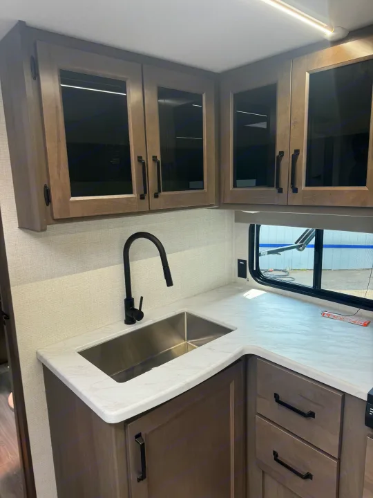 Stylish RV rental kitchen featuring a modern sink, black faucet, and sleek cabinetry.. Grand Design Transcend Xplor 2024