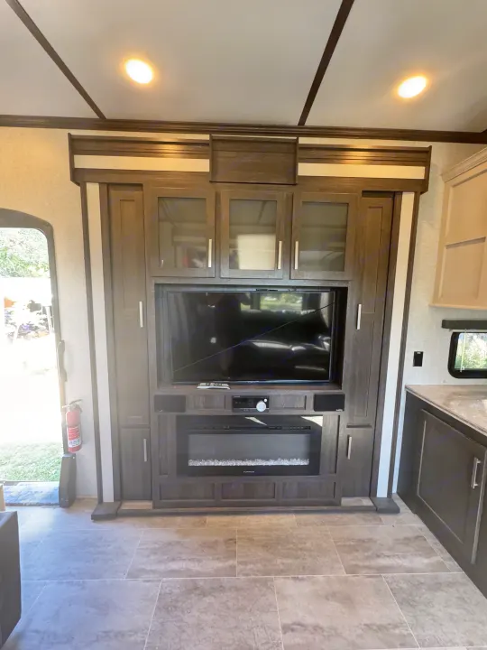RV rental: Inside a modern RV, featuring a built-in entertainment center with TV, electric fireplace, and ample storage cabinets.. Keystone Raptor 2020