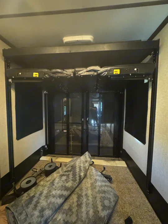 RV rental toy hauler's spacious rear garage area with folded bunk beds/sofas and a large ramp door.. Keystone Raptor 2020