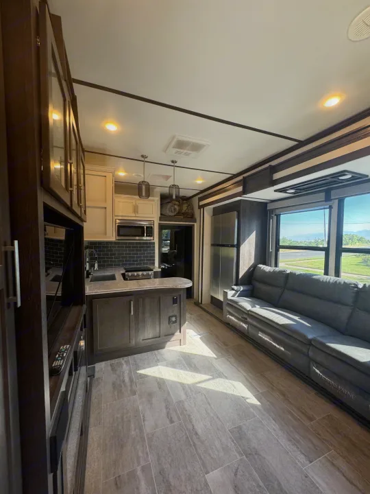 Spacious RV rental interior with a modern kitchen, comfortable seating, and bright views through large windows.. Keystone Raptor 2020
