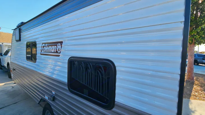 Side view of a clean Coleman travel trailer RV rental, gleaming in the sun. Ideal for family camping adventures.. Coleman 17b 2024