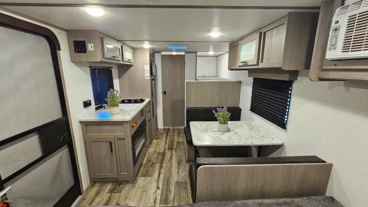 Bright RV rental interior: kitchen with fireplace, dinette, bunk beds, and AC unit. A modern, functional living space.. Coleman 17b 2024