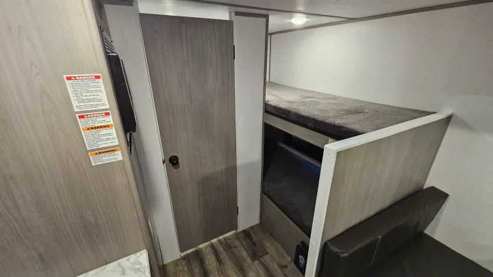 RV rental interior: bunk beds, a wooden door, and essential safety warnings clearly visible on the wall.. Coleman 17b 2024