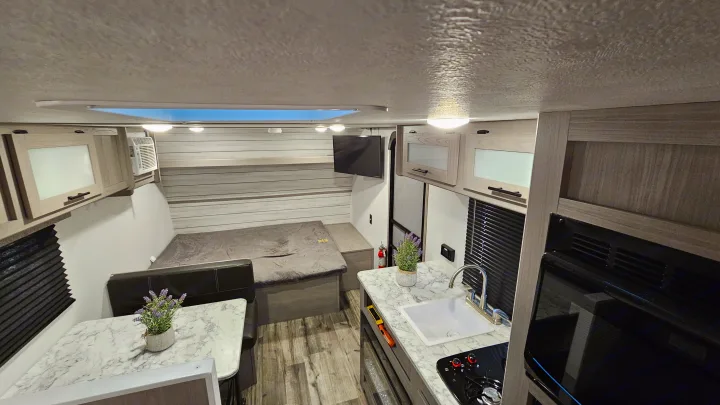 Modern RV rental interior featuring a compact kitchen, dinette, and comfortable sleeping area. Perfect for travel adventures.. Coleman 17b 2024