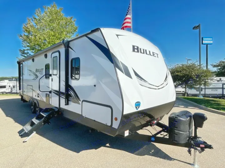 White Bullet travel trailer with steps down and propane tanks, ready for an RV rental adventure.. Keystone RV Bullet Ultra Lite 2021