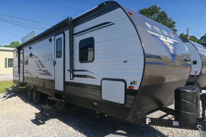 Silver and black Puma travel trailer, ideal for rv rental, shown from the side with its awning, entry steps, and distinct front design.. Palomino Puma 2022