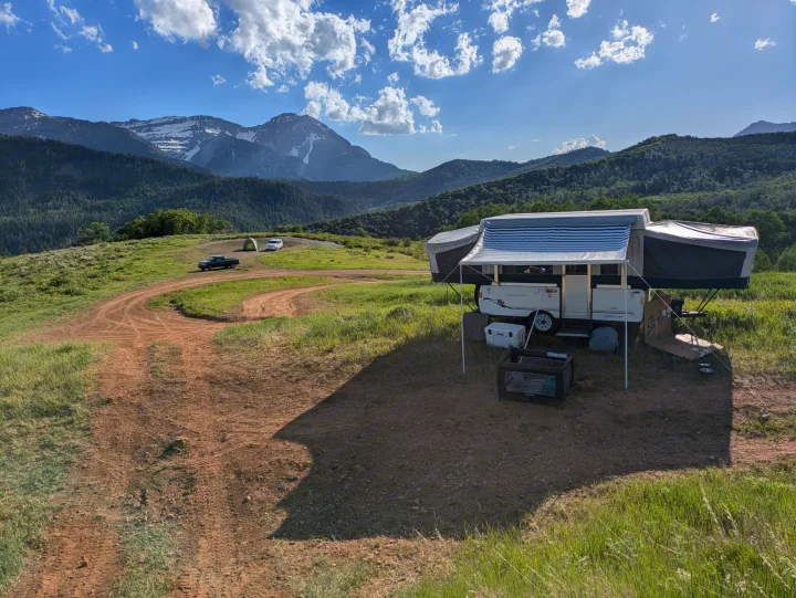Enjoy mountain views with your RV rental. This pop-up camper is set up for a family camping trip, with a truck and tent nearby.. Fleetwood Sedona 2004