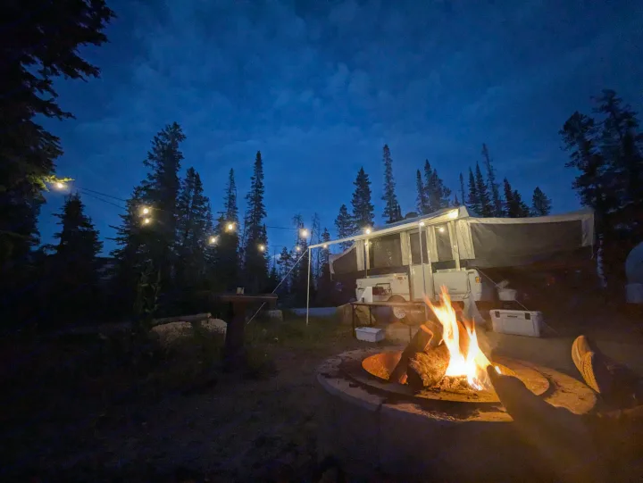 Cozy RV rental pop-up camper setup at night, with string lights and a warm campfire crackling under a deep blue sky.. Fleetwood Sedona 2004