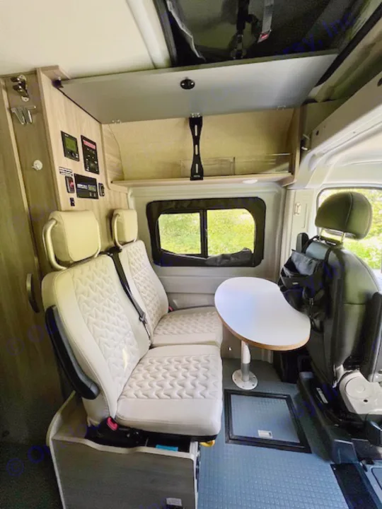 Inside a modern RV rental: light seating, flexible table, and wall controls in this compact camper van.. Winnebago Winnebago 2023