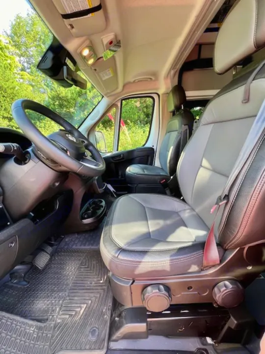 Front interior of an RV rental van, featuring two-tone seats, steering wheel, and clean floor mats. Ready for travel.. Winnebago Winnebago 2023