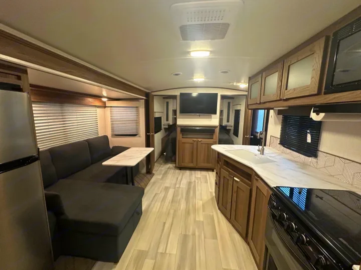 Inside a modern RV rental, featuring a full kitchen, comfortable L-shaped sofa, and dining area.. Cruiser RV MPG 2500bh 2024